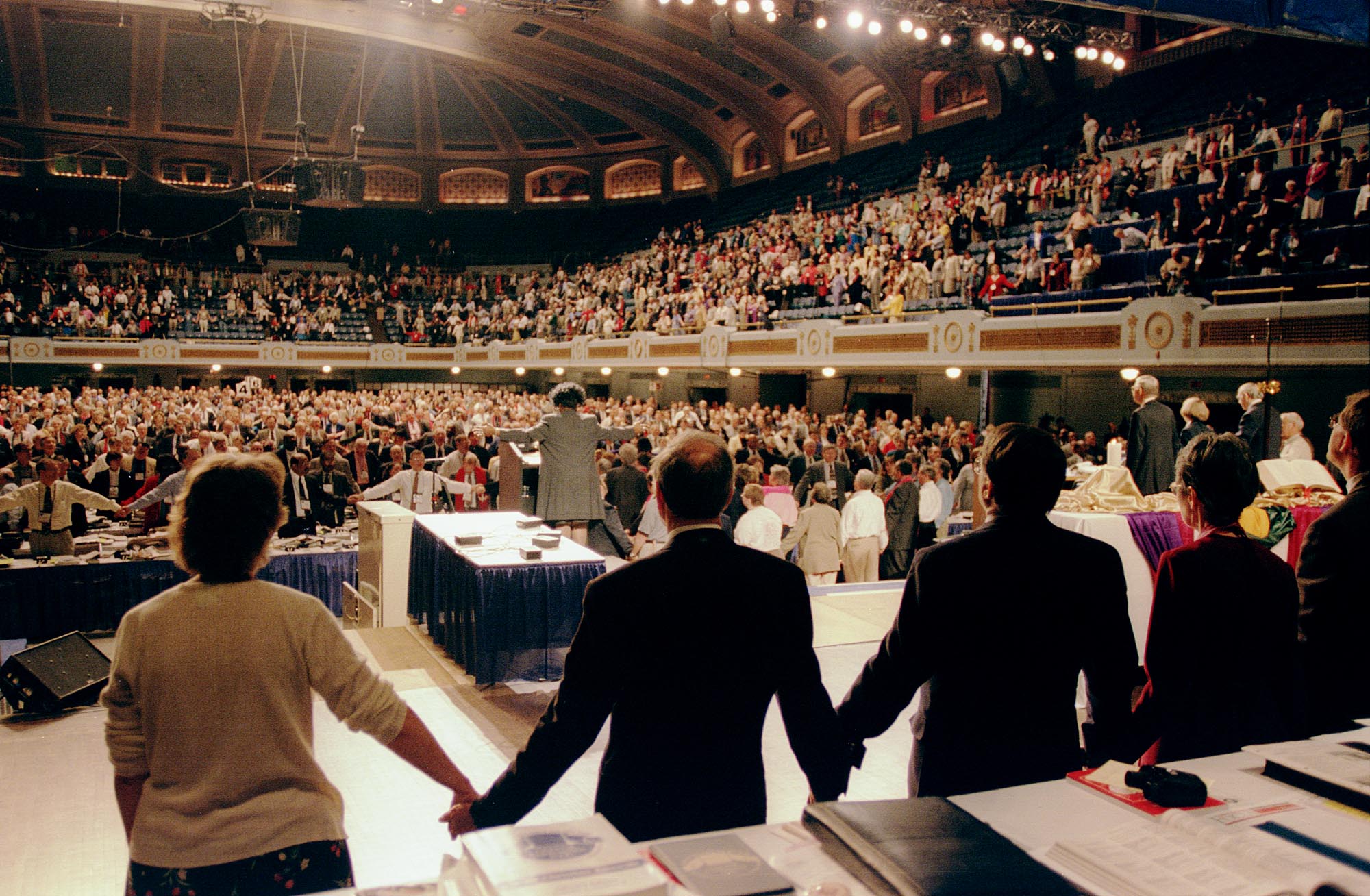 Delegates and guests to the United Methodist Church's 2000 General Conference join hands in song during a break in conference proceedings caused when people protesting the church's anti-homosexual policies blocked the aisles. A UMNS photo by John C. Goodwin 