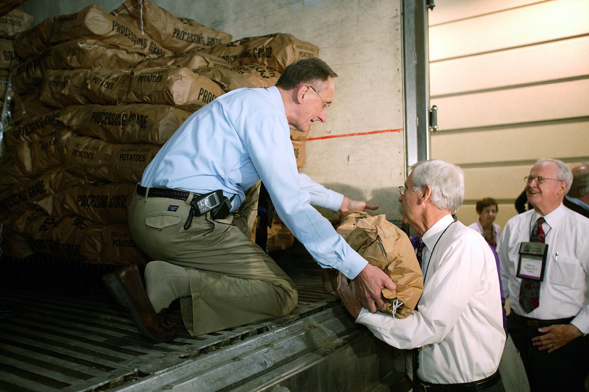 United Methodist Bishop Donald A. Ott (left) hands a sack of potatoes to Bishop Marshall L. (Jack) Meadors, Jr. during a Potato Drop outside the David L. Lawrence Convention Center in Pittsburgh, site of the denomination's 2004 General Conference. Preparing to receive the next sack is Bishop Ray Owen (right). The event, sponsored by the General Commission on United Methodist Men and the Society of St. Andrew, will help feed 120,000 of the city's hungry. A UMNS photo by Mike DuBose.
