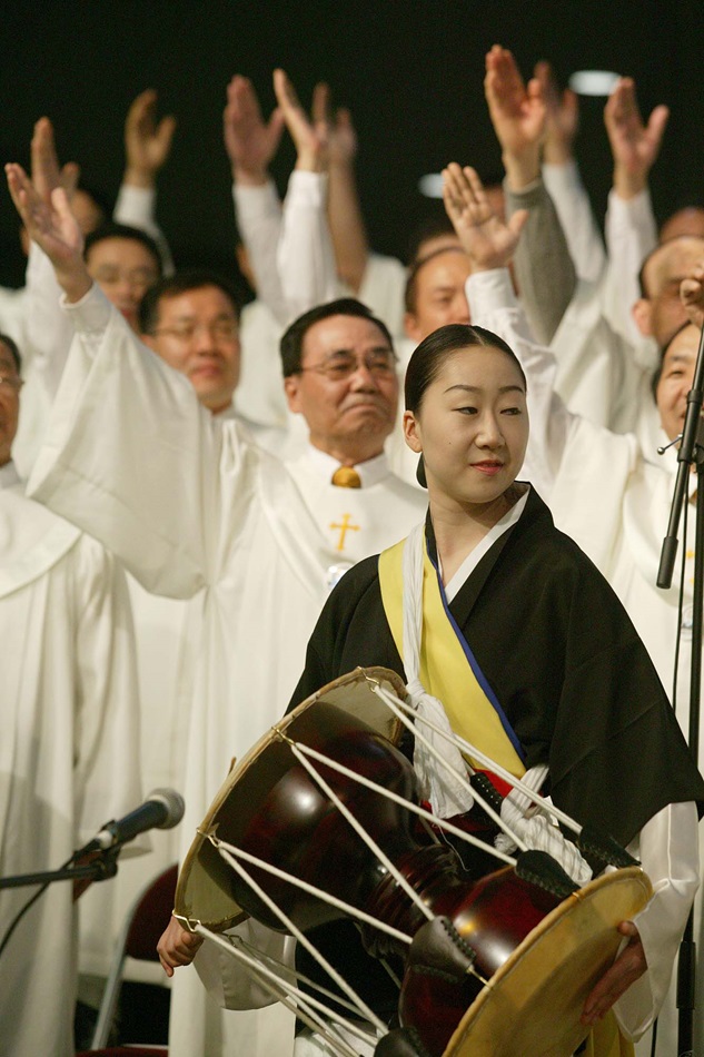 Yu Sun Kwang, flanked by other members of the choir from First United Methodist Church in Flushing, N.Y., plays a Korean drum during worship on May 3 at the denomination's 2004 General Conference in Pittsburgh. A UMNS photo by Mike DuBose.