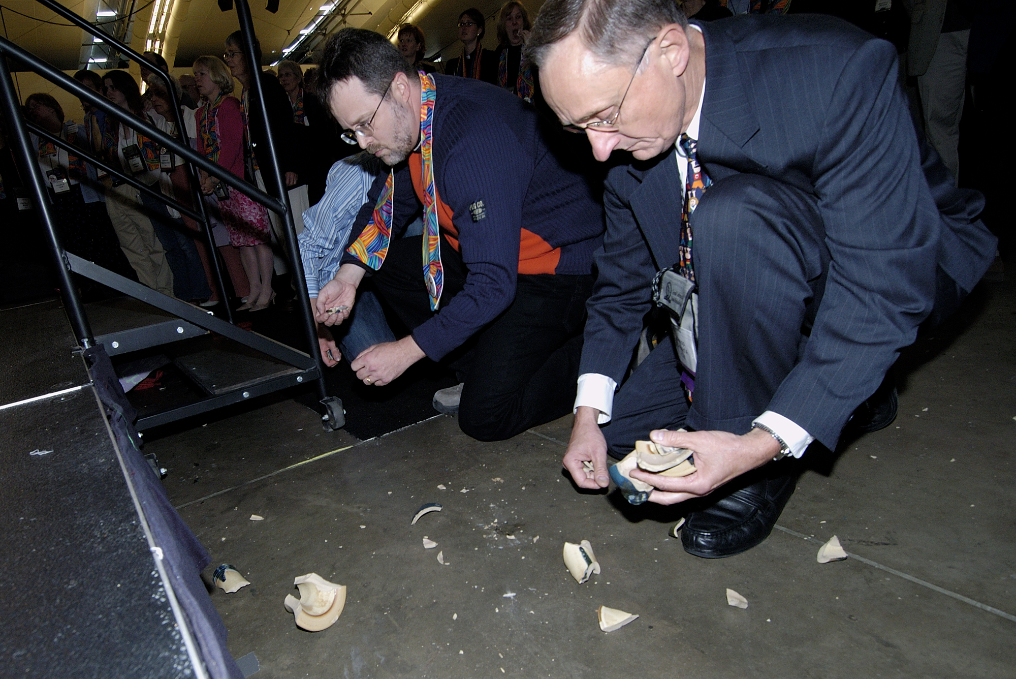 Bishop Donald A. Ott (right) picks up pieces of a communion chalice intentionally broken during a protest after delegates to the 2004 United Methodist General Conference in Pittsburgh maintained language in the church's Book of Discipline that the practice of homosexuality is "incompatible with Christian teaching." A UMNS photo by Paul Jeffrey.