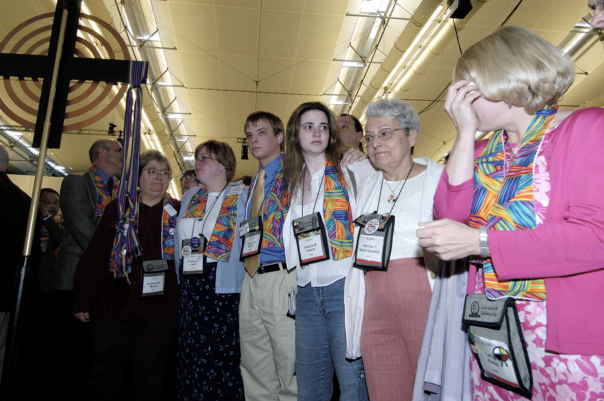 Supporters of gay men and lesbians mourn after delegates to the 2004 United Methodist General Conference in Pittsburgh voted to maintain language in the church's Discipline that the practice of homosexuality is "incompatible with Christian teaching." Many wearing multicolored scarves, those who supported gays and lesbians remained standing throughout the debate and votes. A UMNS photo by Paul Jeffrey.