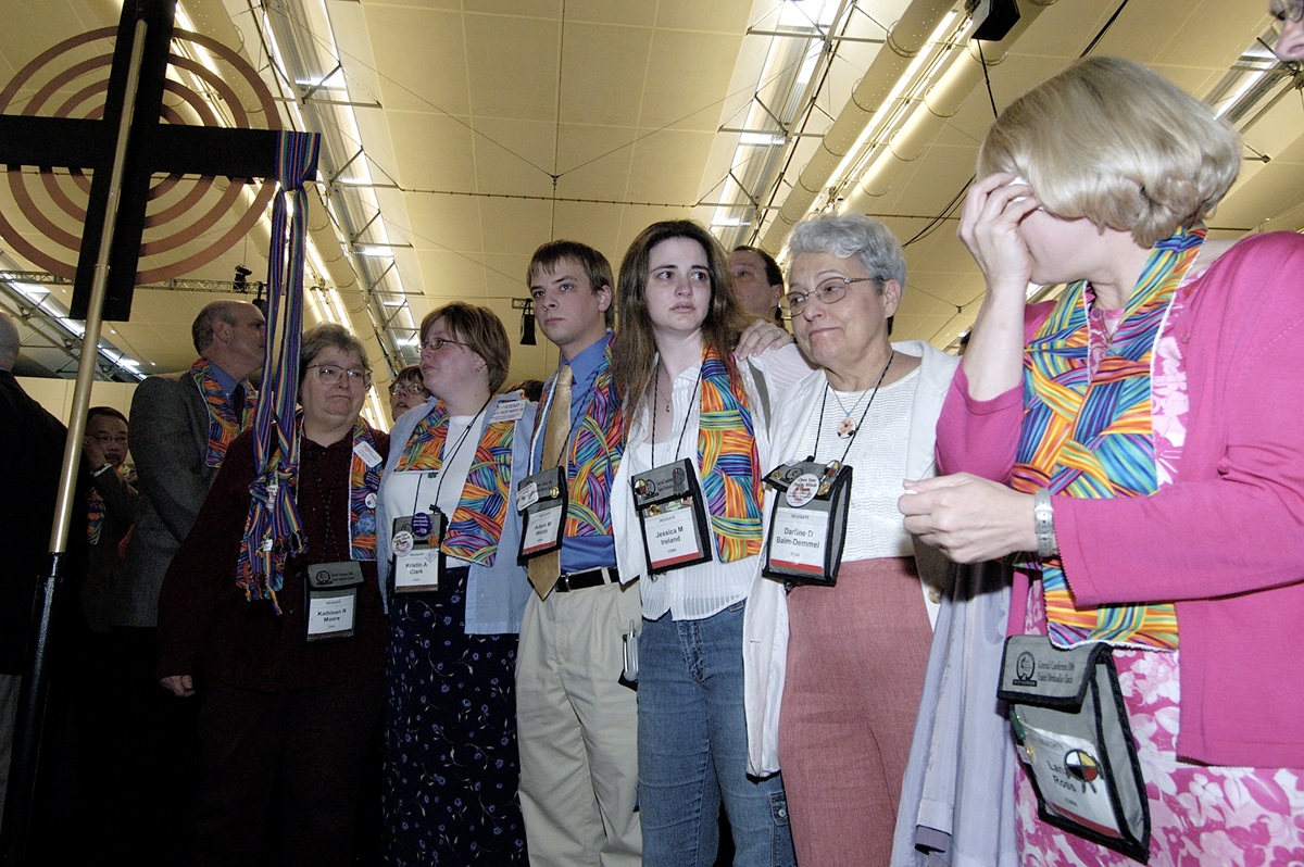 Supporters of gay men and lesbians mourn after delegates to the 2004 United Methodist General Conference in Pittsburgh voted to maintain language in the church's Discipline that the practice of homosexuality is "incompatible with Christian teaching." Many wearing multicolored scarves, those who supported gays and lesbians remained standing throughout the debate and votes. A UMNS photo by Paul Jeffrey.