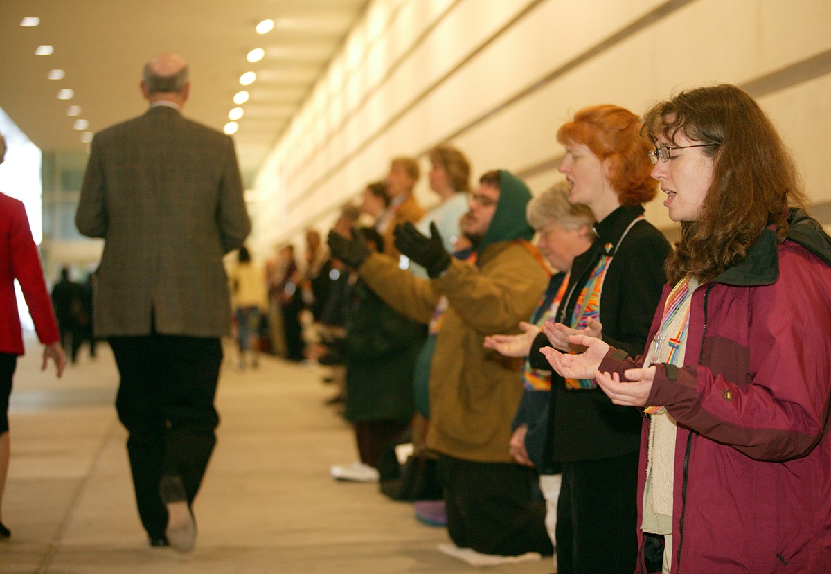 Laura Folkwein (right) and Elizabeth Brick (second from right) pray during a protest at General Conference. A UMNS photo by Mike DuBose.