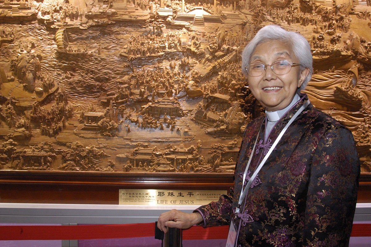 The Rev. Cao Sheng-jie, president of the China Christian Council, stands next to a giant wood carving that is part of the “A Lamp to My Feet, A Light to My Path,” a Bible ministry exhibition from China.  A UMNS photo by John Goodwin.  