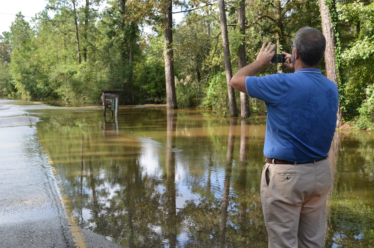 The Rev. Tom Hazelwood of the United Methodist Committee on Relief takes pictures of the flooded road leading to Lee’s Landing United Methodist Church.