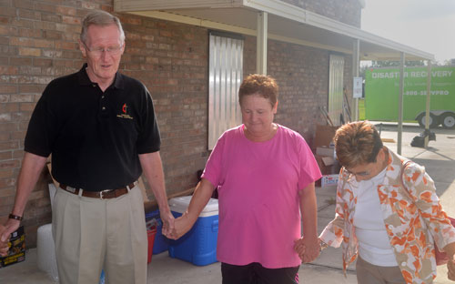 The Rev. Don Cottrill and Bishop Cynthia Fierro Harvey (right) pray with the Rev. Regina Hickman in front of First United Methodist Church in LaPlace, La. The church had a foot of standing floodwater during Hurricane Isaac. Photos courtesy of Betty Backstrom.