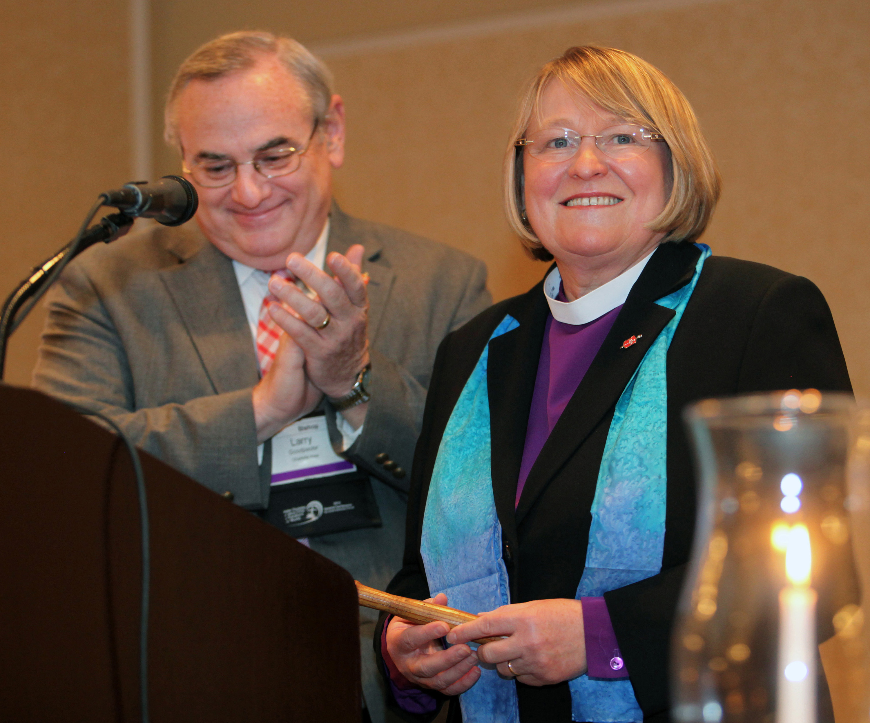 Bishop Rosemarie Wenner, Council of Bishops president, accepts the gavel from the former council president, Bishop Larry M. Goodpaster, in a “passing of the gavel” ceremony April 26 in Tampa, Fla. A UMNS file photo by Kathleen Barry.