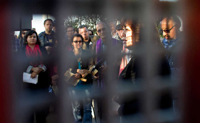 United Methodist Bishop Minerva Carcaño is framed by the tightly-spaced mesh of the border fence between San Diego and Tijuana, Mexico last month. Today President Obama made a call for immigration reform to fix a “broken immigration system.”