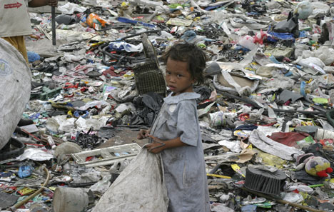 A young girl is surrounded by trash at the dump nicknamed Smokey Mountain in Manila, Philippines. The city's poorest people live in the dump and make their living looking for goods to recycle. 