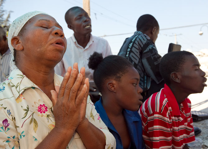 Noel Zierne (left) prays during worship at St. Martin Methodist Church in Port-au-Prince, Haiti. 