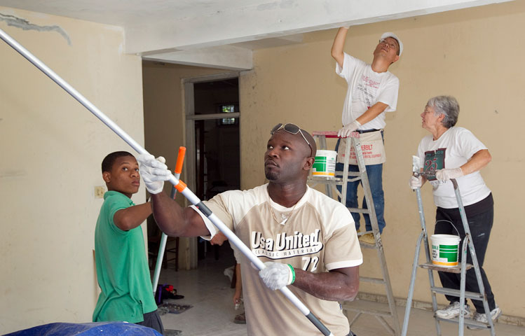 Haitian and U.S. volunteers work together to paint the home of "Sister Paulette" Holly at the Methodist Children's Home orphanage in Port-au-Prince, Haiti. 