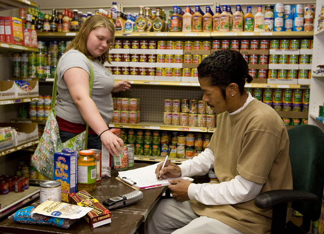 Alfred Hardnett (right) helps Candice K. Mink with her groceries in the food pantry at The Community Enabler Developer ministry in Anniston, Ala.. Photo by Mike DuBose, UMNS.