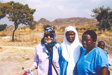Jackson, left, and Nyathipa Khimbi, right, stand with a literacy teacher in Mpalale village, Malawi.