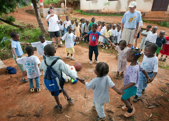 Volunteer in Mission team members Terry Temple (left background) and John Thomas (right background) help lead a game for children outside the Methodist church in Furcy, Haiti. 