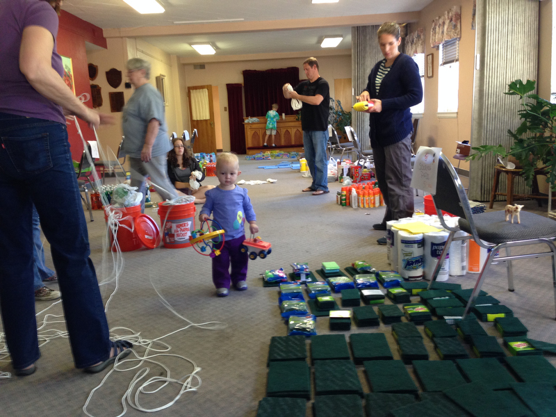 Members of Highlands United Methodist Church in Denver assemble cleaning buckets for those affected by the Colorado floods, while toddler Emma, daughter of two of the volunteers (not pictured) plays amid the cleaning supplies. A UMNS photo by Bradley Laurvick.