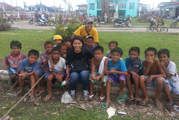 Children from Dagami, Leyte, gather around United Methodist Communications team members April Mercado (front, center) and Ernani Celzo (back). These children are survivors of Typhoon Yolanda. Photo courtesy of April Grace Mercado.