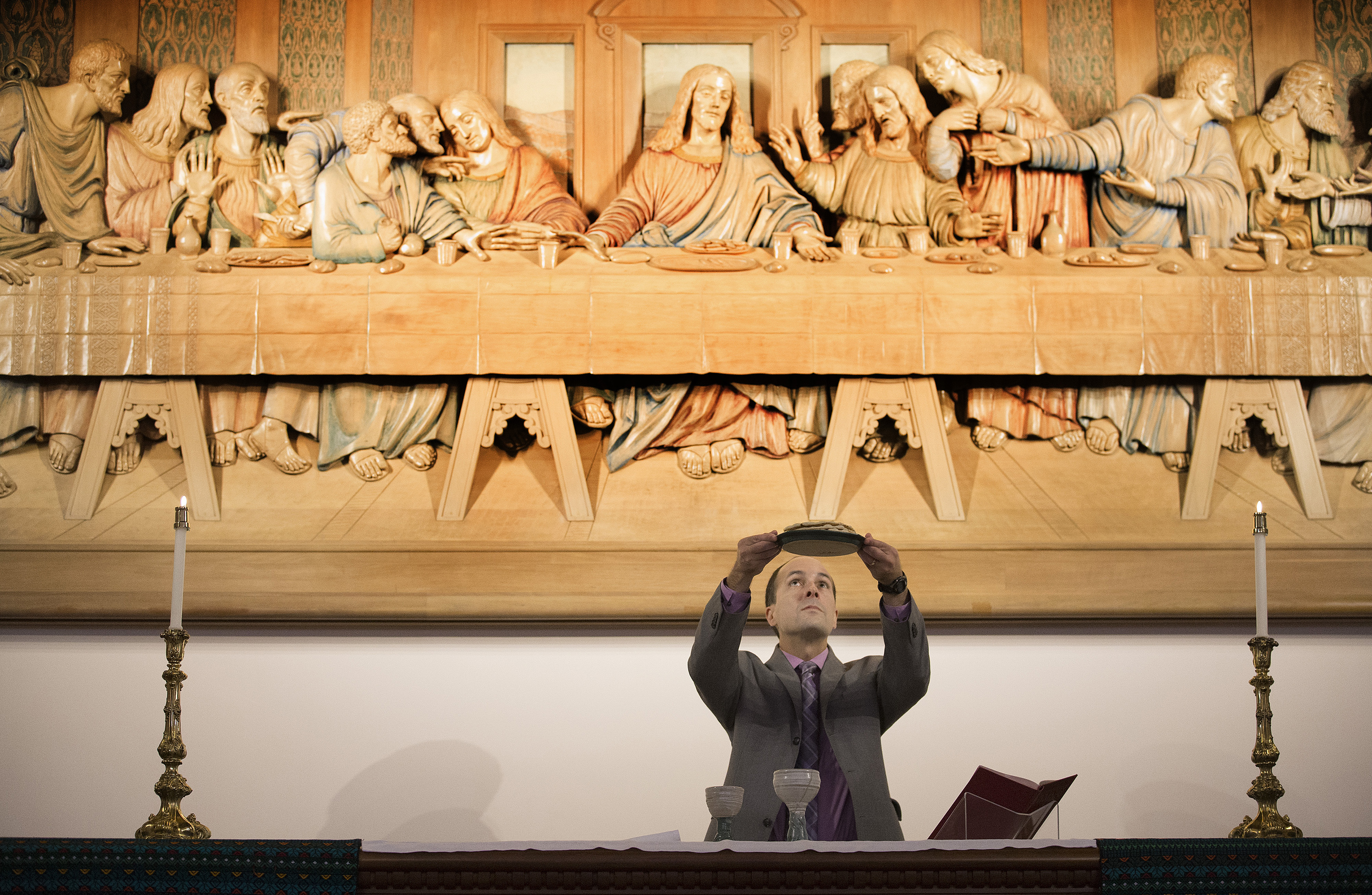 The Rev. Edgardo Colón-Emeric blesses the elements of Holy Communion in front of a woodcarving of Leonardo da Vinci's “The Last Supper” at the Upper Room Chapel in Nashville, Tenn. A UMNS photo by Mike DuBose.