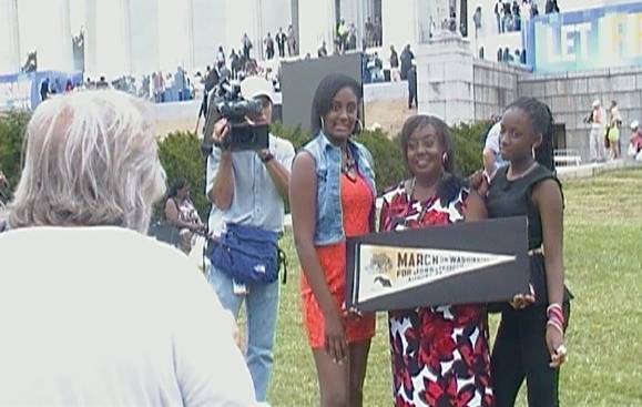 Edith Lee-Payne (holding banner) poses with her granddaughters Destiny (left) and Dejai during the 50th anniversary of the March on Washington. Making their family portrait is Rowland Scherman, who made an iconic photograph of Edith during the 1963 march. 