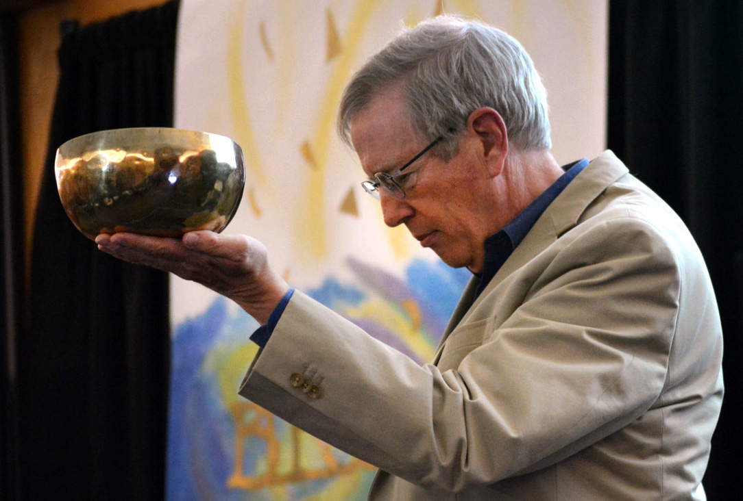 Bill Everett holds a Tibetan Buddhist singing bowl to “summon the gathering to peace” during the opening of the Peace Conference.  Photo by Michael Rich. 