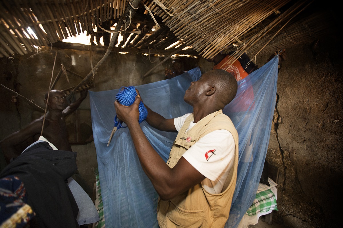  Ernest Jusu, a nurse working with The United Methodist Church's Imagine No Malaria campaign, helps hang a new, insecticide-treated mosquito net at the home of Peter Braima in Manjama, near Bo, Sierra Leone. Photo by Mike DuBose, UMNS 