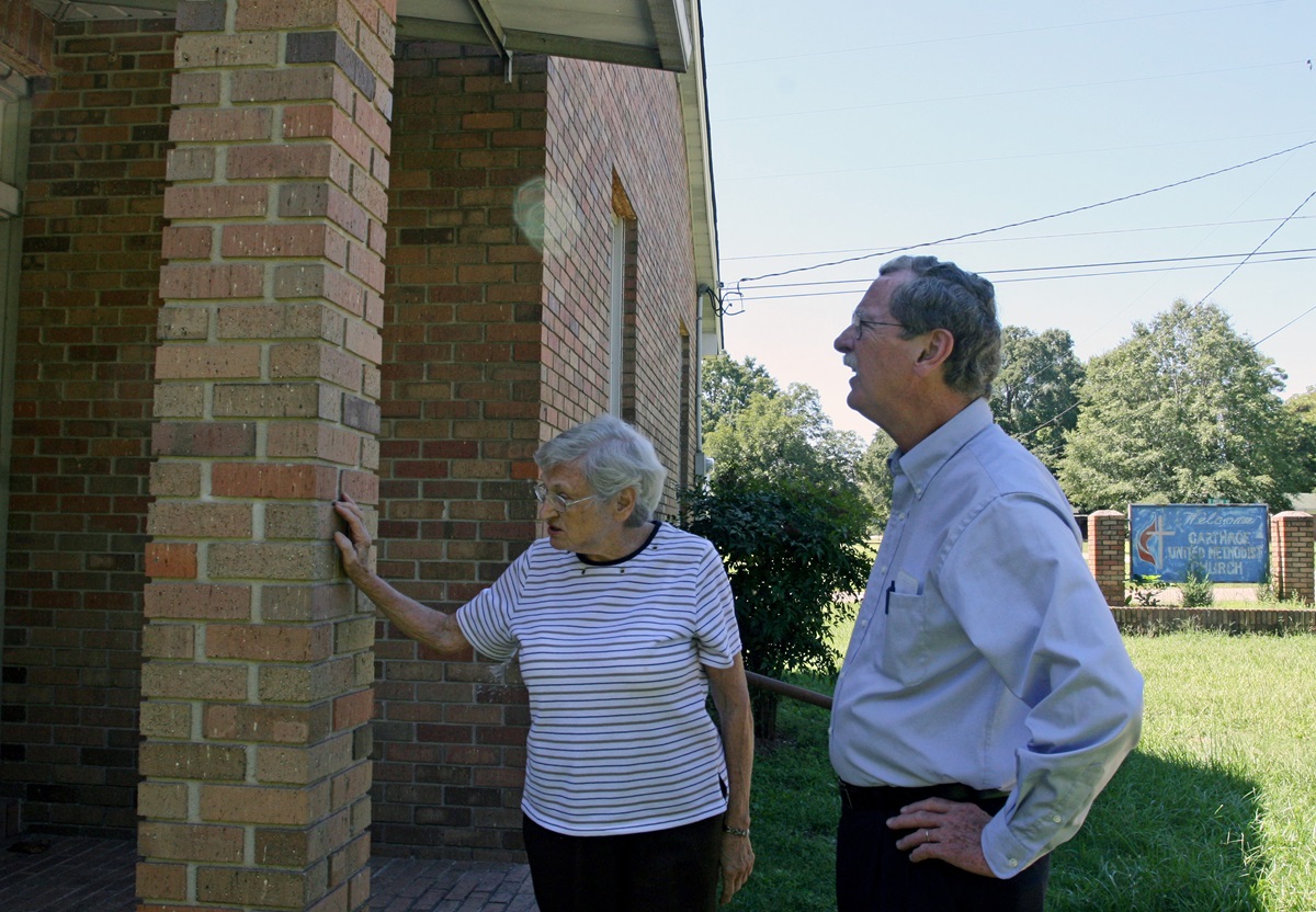 Ida Mae Nutt, the last surviving member of Carthage United Methodist Church, shows the Rev. James Batts some water damage on the brick building. The members of the four churches in the Carthage charge talked about closing the church earlier this year, but Nutt and the others decided to keep the building open for worship once a month. Nutt, with help from Matthews, takes care of the building. Photo by Heather Hahn, UMNS.