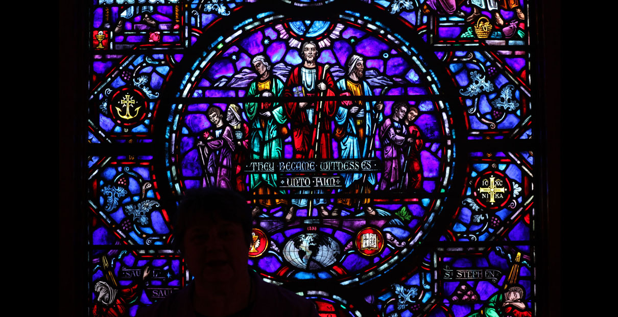 A woman stands silhouetted against a stained-glass window outside The Upper Room chapel.  Photo by Kathleen Barry, UMNS.