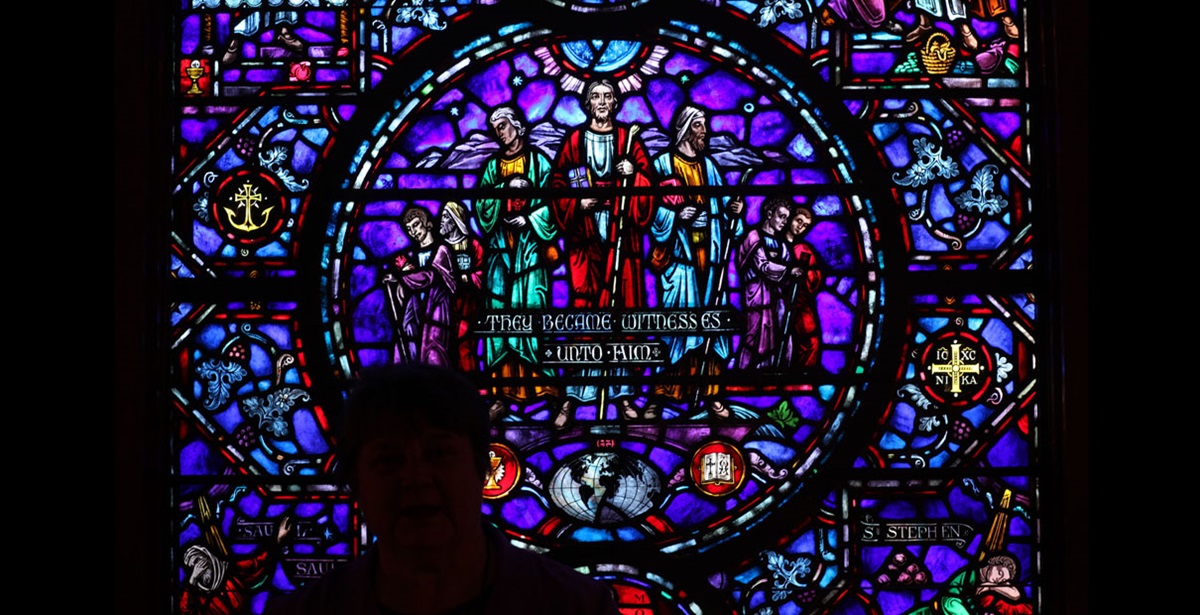 A woman stands silhouetted against a stained-glass window outside The Upper Room chapel.  Photo by Kathleen Barry, UMNS.