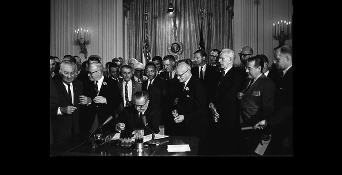President Lyndon B. Johnson signs the 1964 Civil Rights Act as Martin Luther King, Jr., and others, look on. Photo by Cecil Stoughton, White House Press Office, Wikimedia Commons.