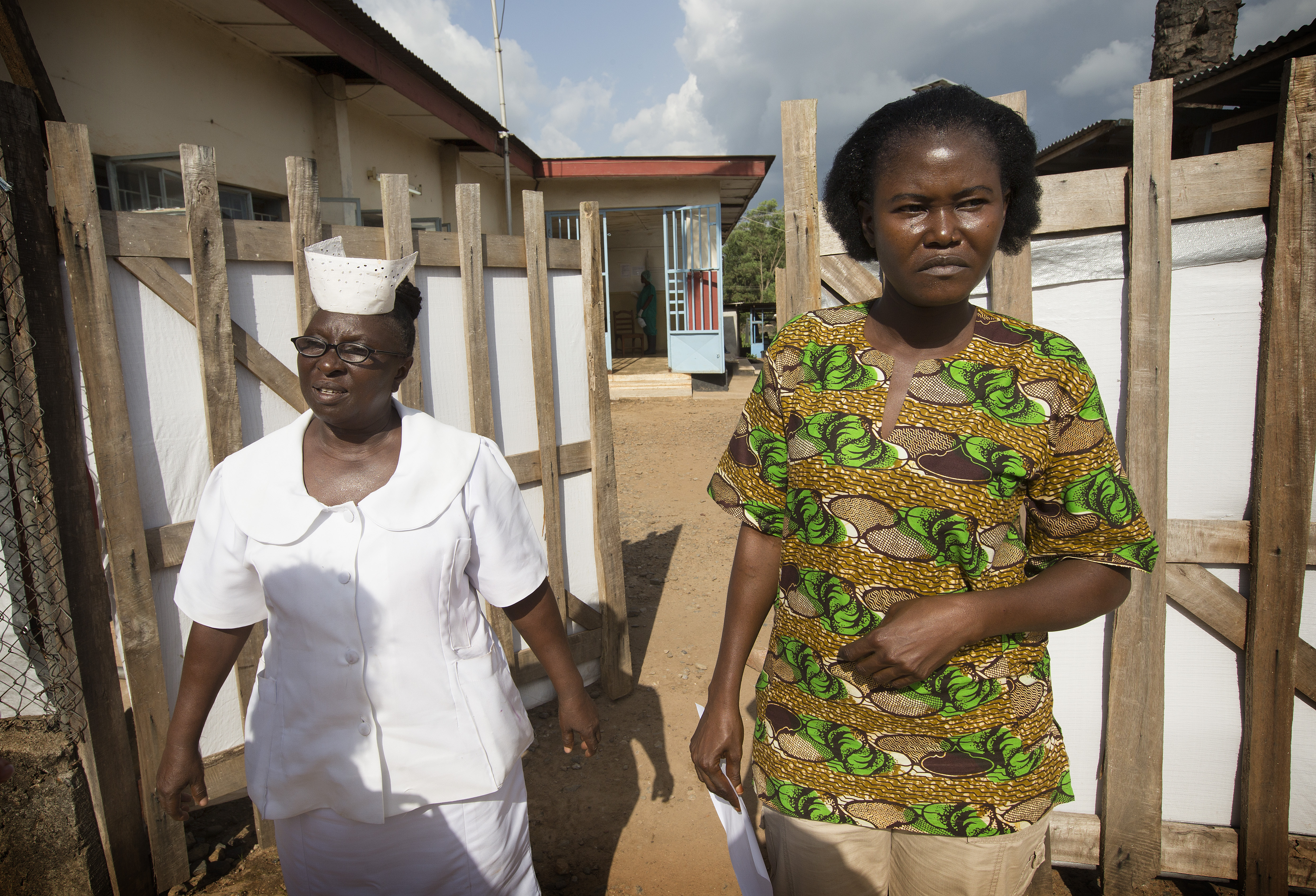 Mbalu Fonnie, head nurse in the hemorrhagic fever ward, and nurse Veronica Karoma describe efforts to contain the Ebola virus as she stands outside the gates to the isolation ward at the government hospital in Kenema, Sierra Leone. 