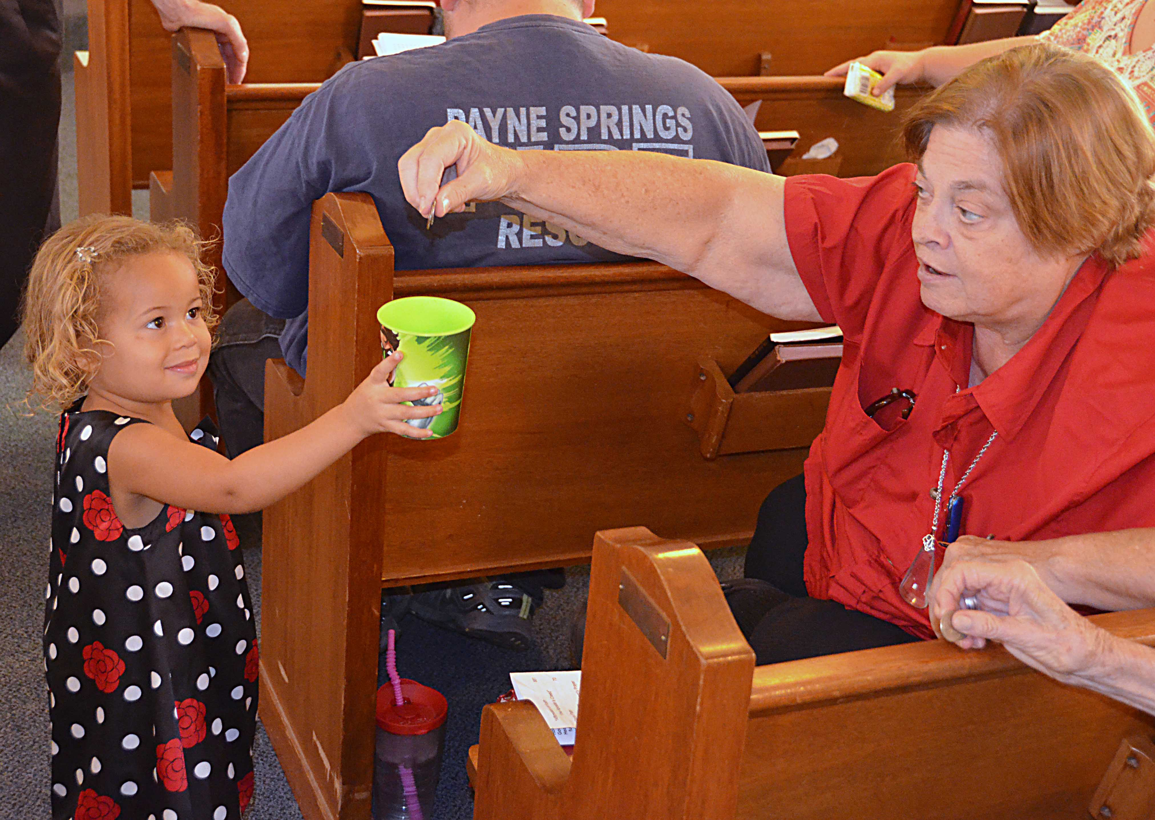 Alaia Williams collects a quarter from member Dennise Richardson at Aley United Methodist Church in Seven Points, Texas. Photo by Richard Browne.