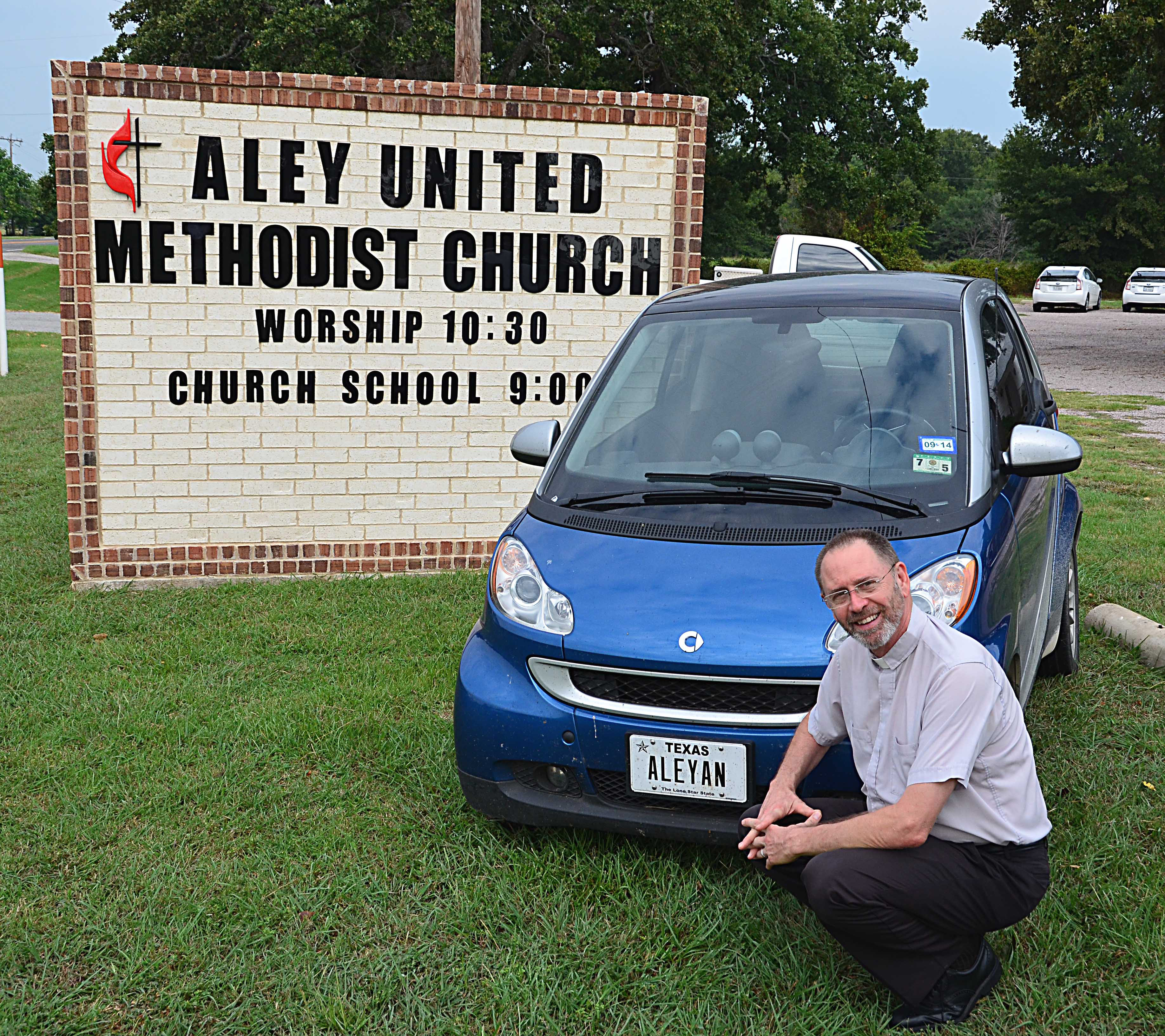 The Rev. Eston Williams with his Aleyan license plate in front of Aley United Methodist Church in Seven Points, Texas.