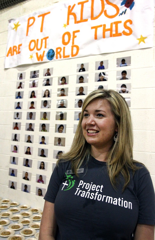 Courtney Aldrich, director with Project Transformation, stands by a wall showing photos of the kids in the Project Transformation camp at Antioch United Methodist Church. 