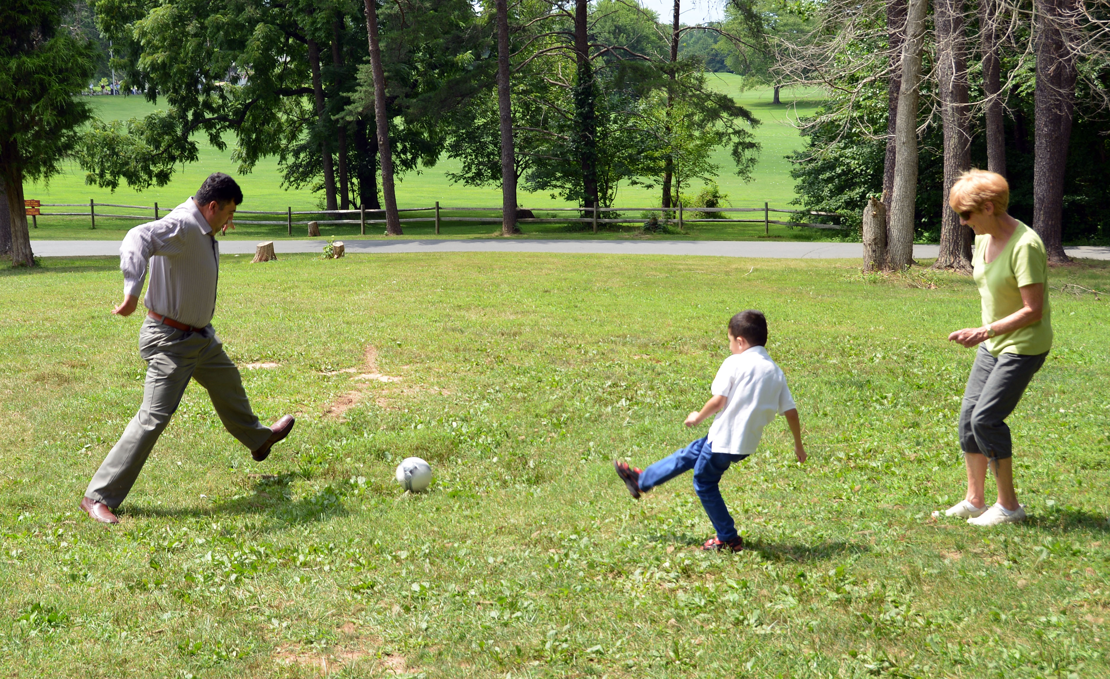 Hameed (left) and his son, Rawof, kick a soccer ball with church friend Margene Sims. 