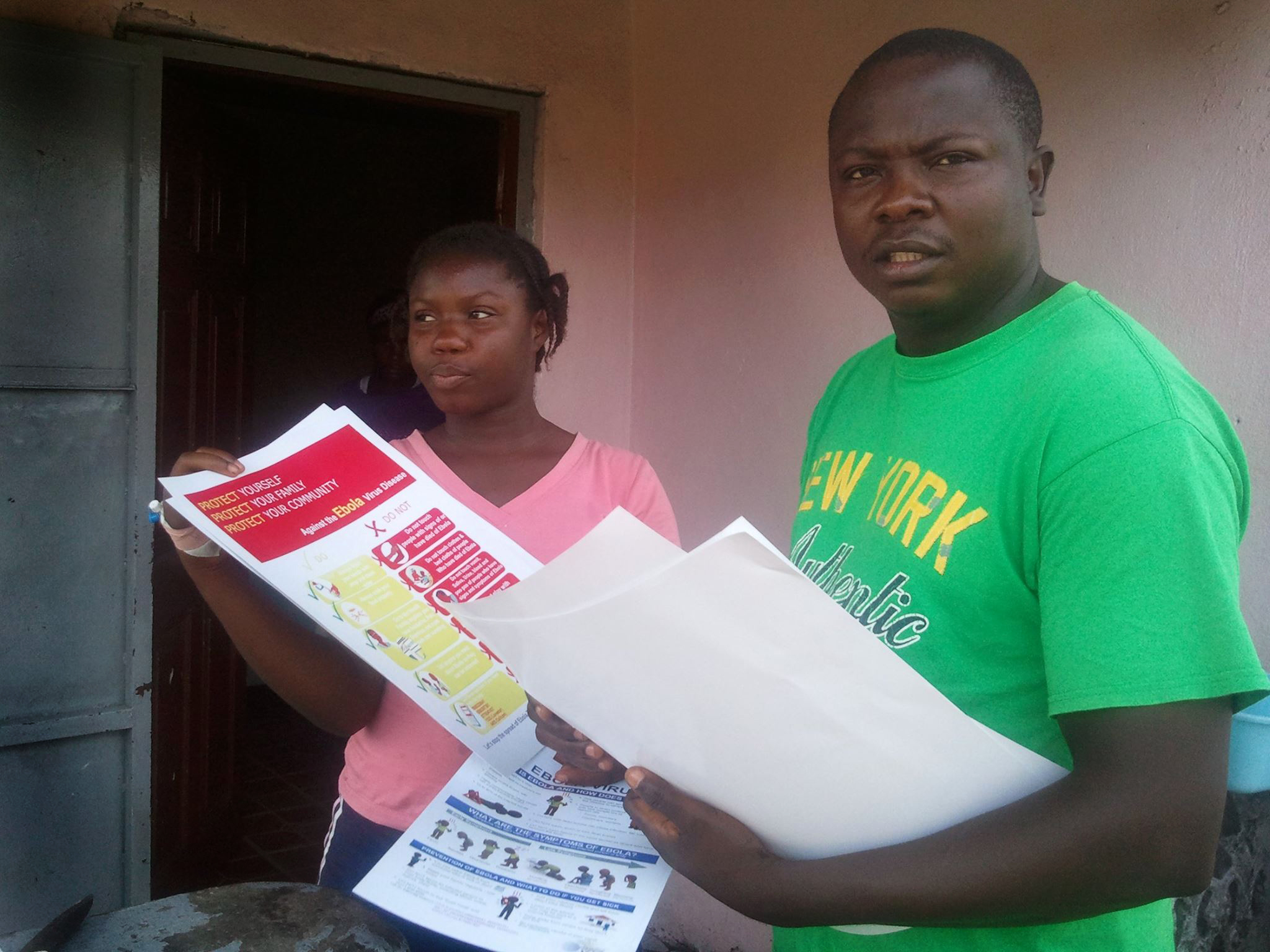  Christian Zigbuo (right) works to distribute printed information to educate people in Liberia  about the Ebola virus.  