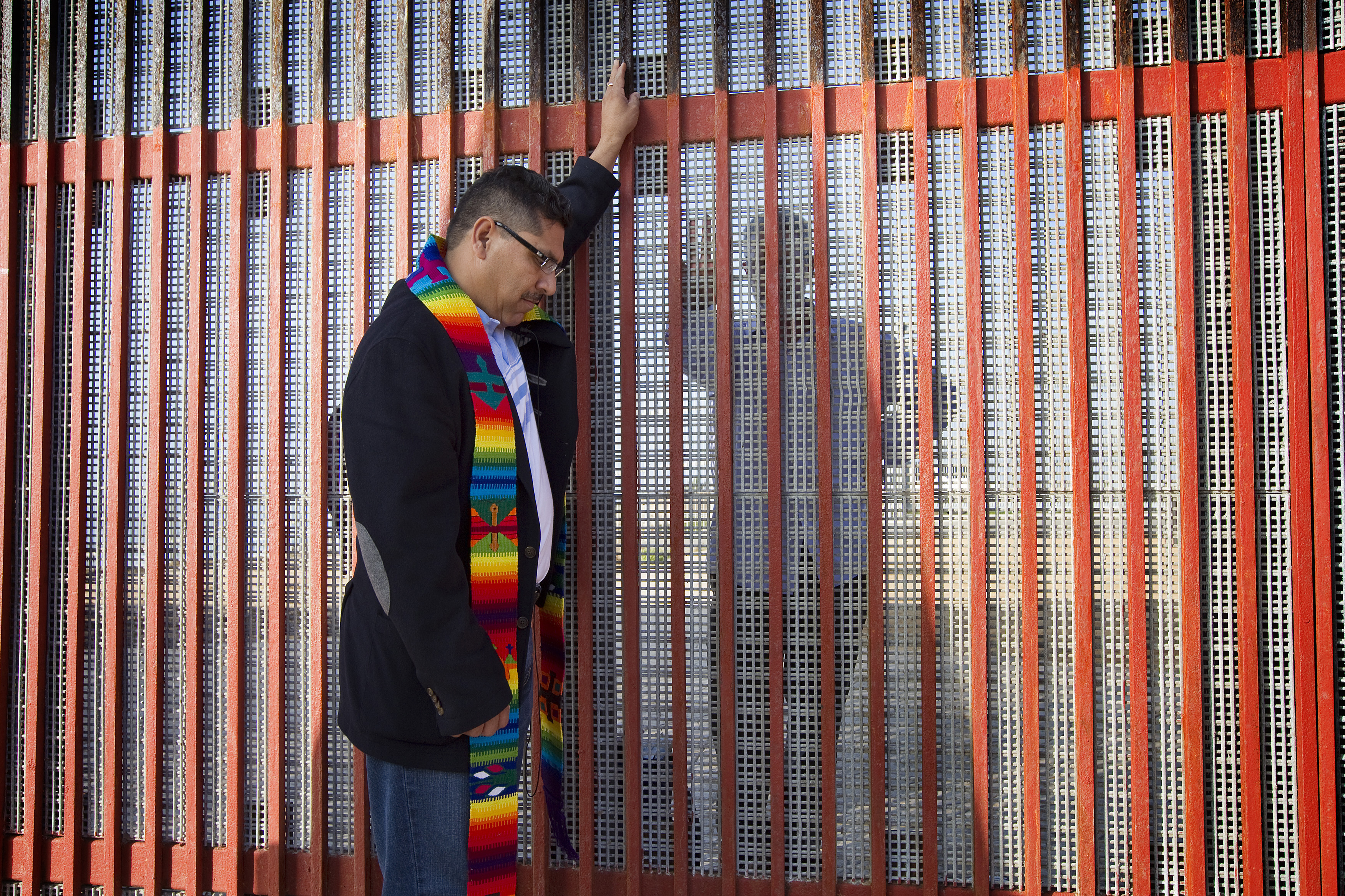 The Rev. Saul Montiel (right) prays during a cross-border service of Holy Communion at El Faro park in Tijuana, Mexico. Montiel is on the Mexico side of the border. 