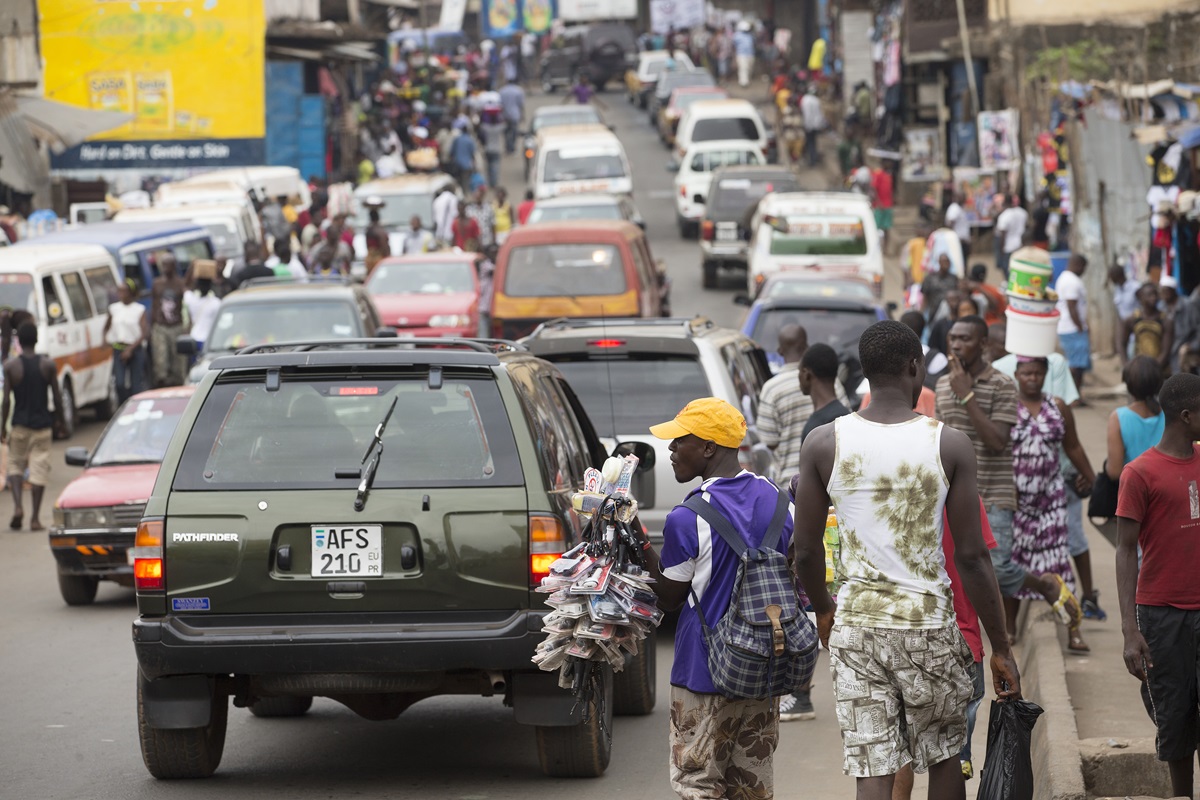 Vehicles and pedestrians make their way along a crowded street in Freetown, Sierra Leone.
