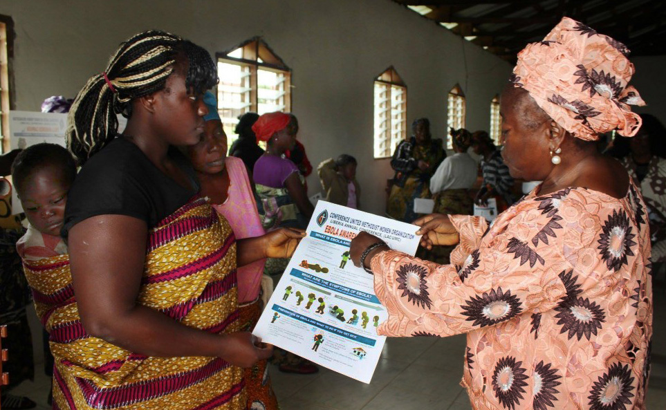(At right) Taryonnoh N. Doe, vice president of Liberia United Methodist Women, shows an Ebola awareness poster as part of the UMW’s anti-Ebola campaign.  