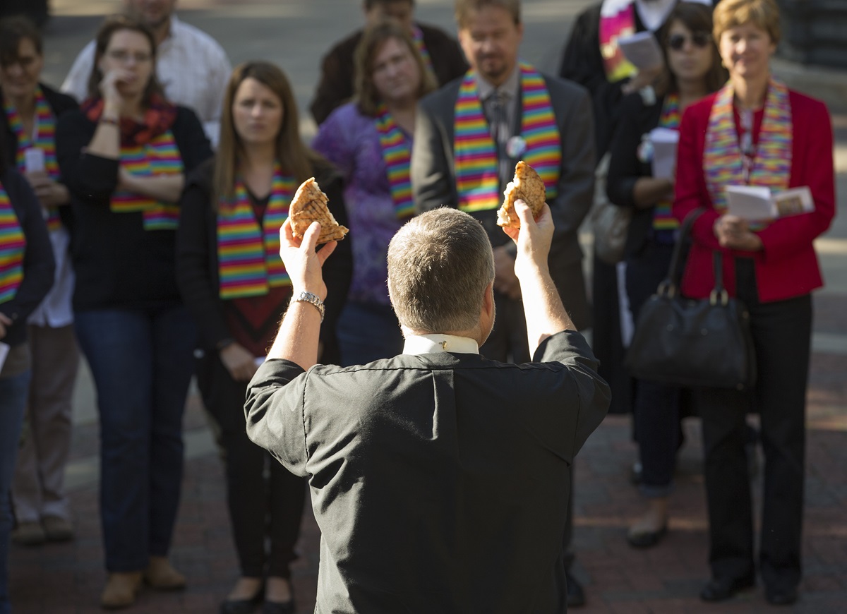 The Rev. Johnny Jeffords blesses the elements of Holy Communion during a prayer service for unity at Court Square Park in Memphis, Tenn., prior to the Rev. Frank Schaefer's appearance before the United Methodist Judicial Council. Schaefer is directly behind Jeffords' right hand. 