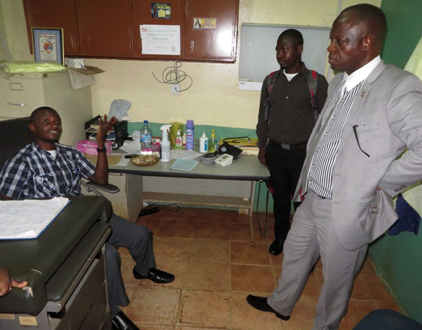 Bishop John K. Yambasu (standing, right) and senior conference staff visit and pray with Dr. Martin Salia (sitting) after a patient admitted to Kissy General Hospital died of Ebola. 