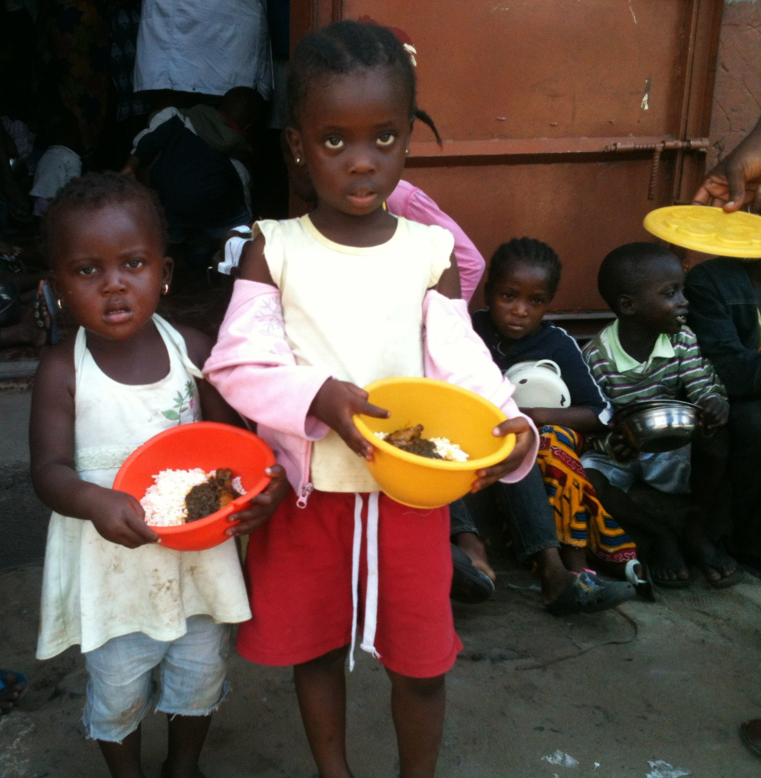 Two young girls receive meals from a program started by a United Methodist pastor for children living in West Point, a slum in Monrovia. 
