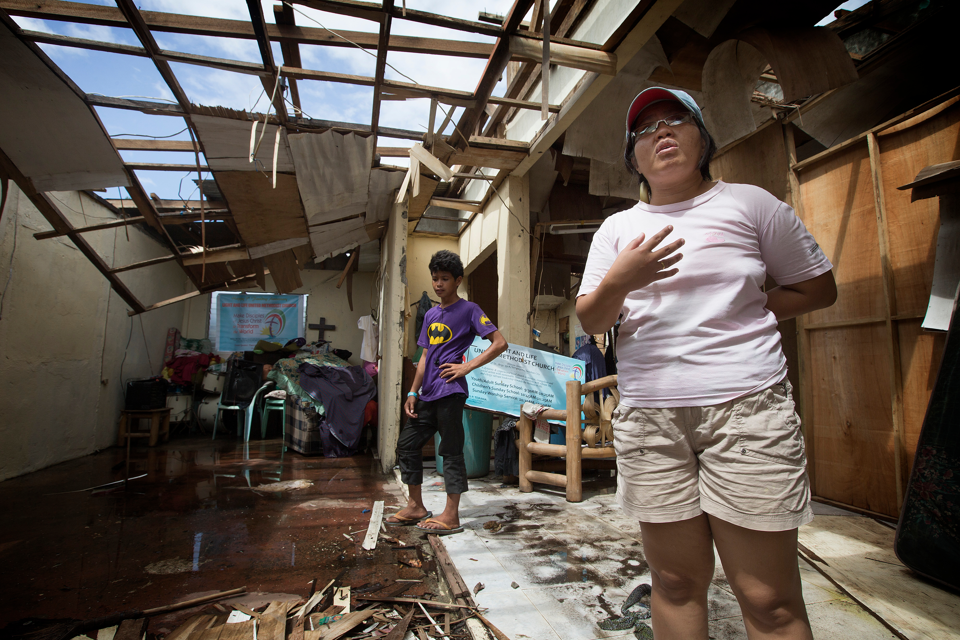 The Rev. Iris Picardal Terana describes how Typhoon Yolanda, also known as Typhoon Haiyan, destroyed Light and Life United Methodist Church in Tacloban City, Philippines in November 2013. The church is using a temporary building one year after the storm. At left is church member Ronell de Juan. File photo by Mike DuBose, UMNS.
