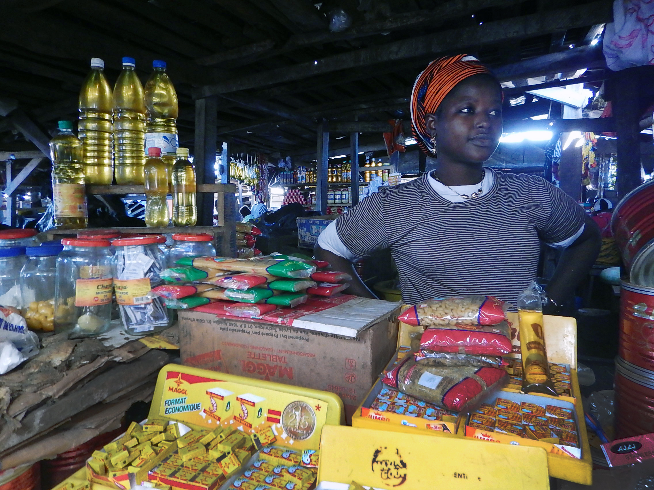 Fanta Touré stands in her stall in the market in Man, Côte d’Ivoire.  Her items for sale range from packaged food to oil and are imported from neighboring Guinea. Photo by Isaac Broune, UMNS