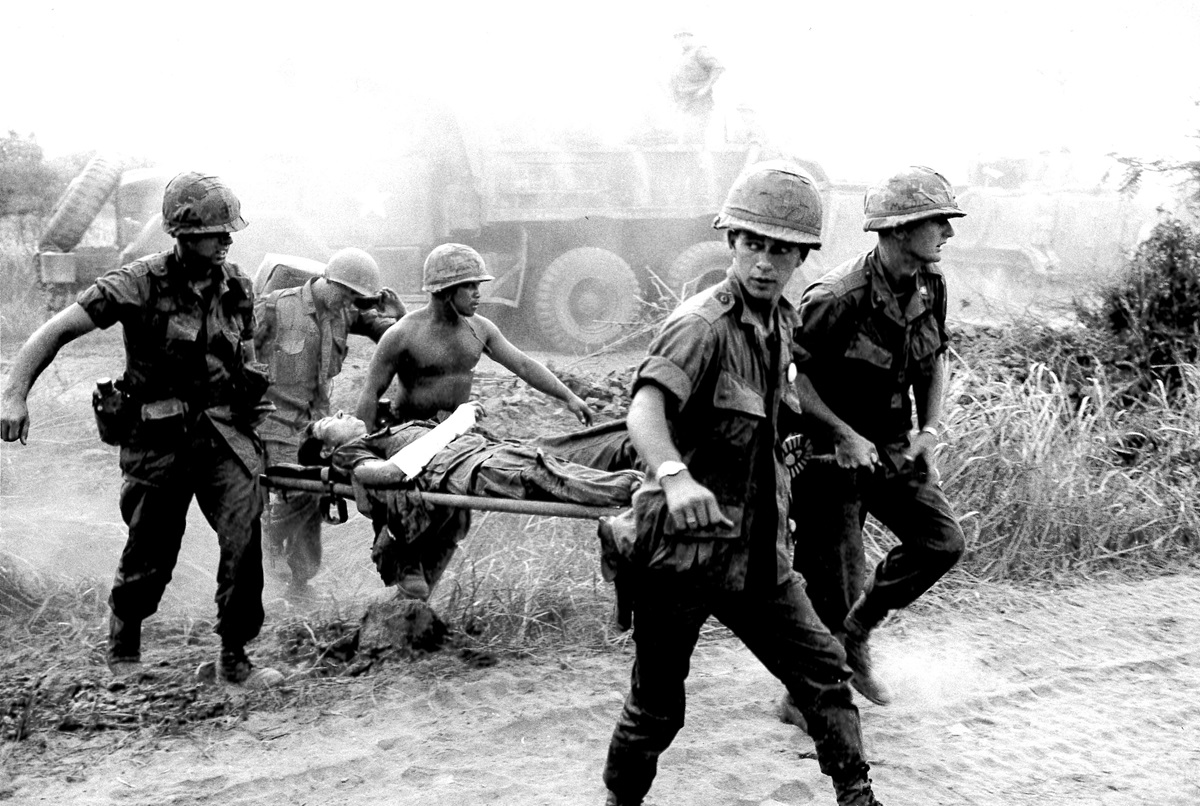 Chaplain Carter (far left) helps bear the wounded man to a medic station before his evacuation to a hospital. 