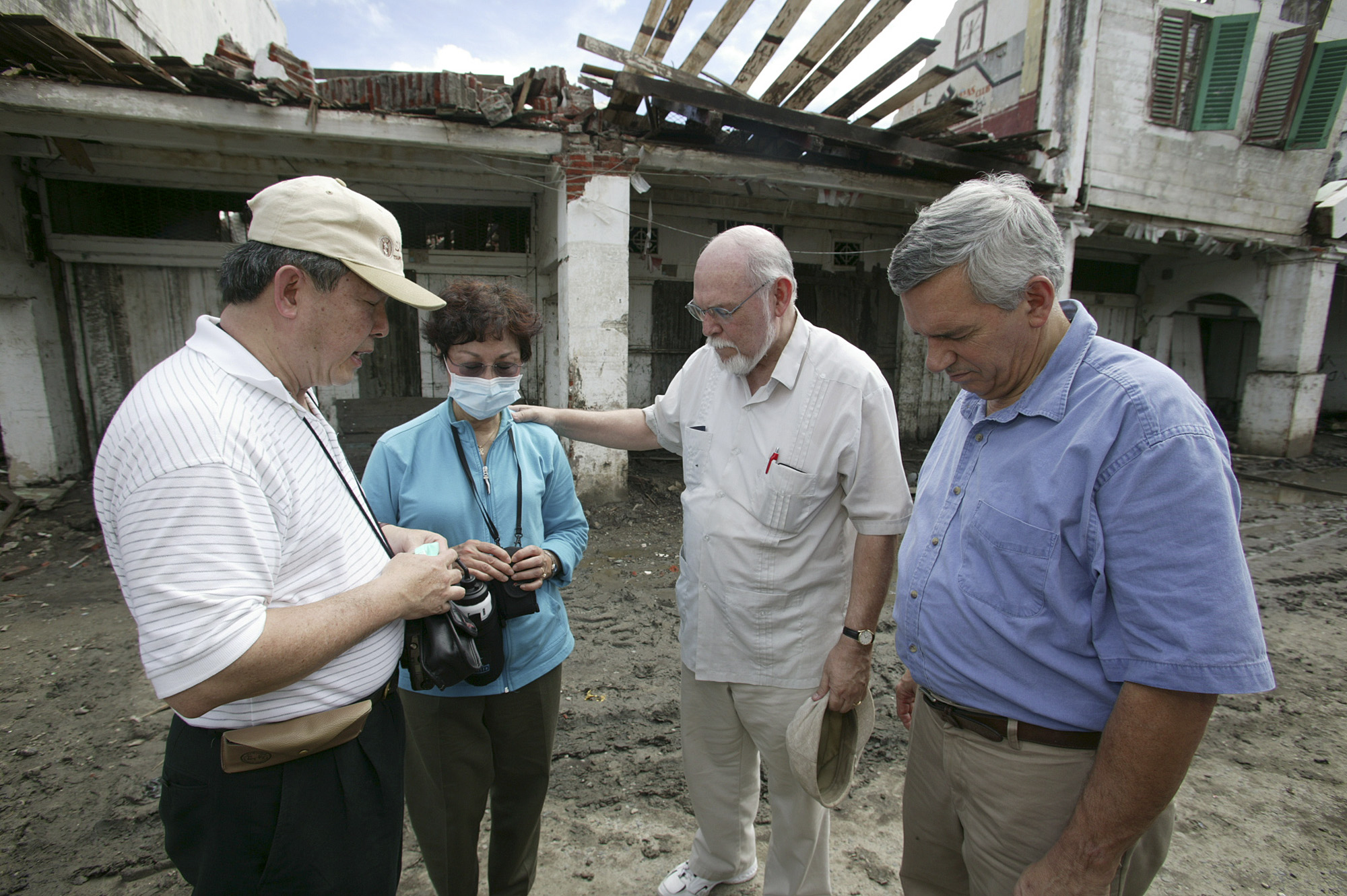 United Methodist Bishop Joel N. Martinez (second from right) prays with (from left) the Rev. Henry Leono, pastor of St. Paul United Methodist Church in Willingboro, N.J.; Kyung Za Yim, president of the Women’s Division; and the Rev. R. Randy Day, top staff executive of the denomination’s mission board. They are standing in front of the building that once housed the first Methodist congregation, established by Leono’s brother, in Banda Aceh, Indonesia, which was destroyed in the Dec. 26 tsunami. The delegation visited the area three weeks after the disaster.  Photo by Mike DuBose, United Methodist News Service