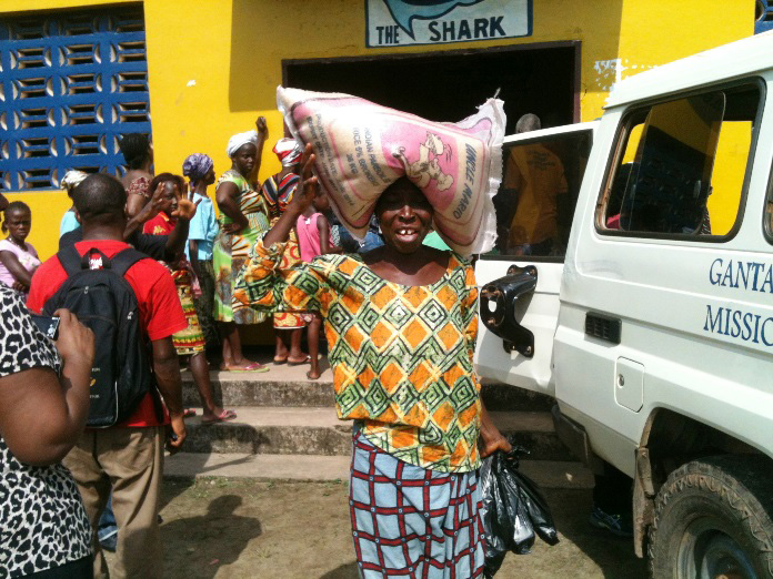 A woman carries a 25-kilogram (55-pound) bag of rice she received through the food distribution in Topoe Village outside Monrovia by the United Methodist Committee on Relief and The United Methodist Church in Liberia. Photo by Julu Swen, UMNS