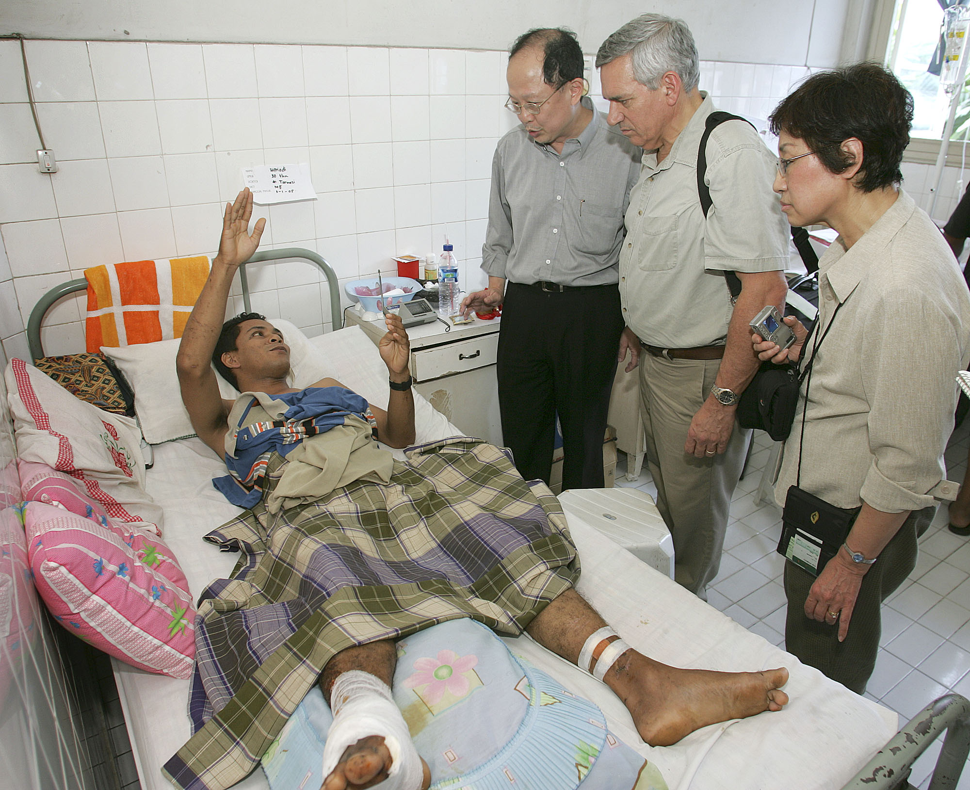 A patient at the Rumah Sakit Methodist Hospital in Medan, Indonesia, describes how he survived the Dec. 26 tsunami that destroyed his home in Banda Aceh. In January, a delegation of mission and communications leaders from the United Methodist church visited areas of Sumatra, Indonesia, near the epicenter of the earthquake that caused the tsunami. From left, center, are Dr. Yohan Pranata, a director of the hospital; the Rev. R. Randy Day, top staff executive of the denomination’s Board of Global Ministries; and Kyung Za Yim, president of the Women’s Division. Photo by Mike DuBose, United Methodist News Service