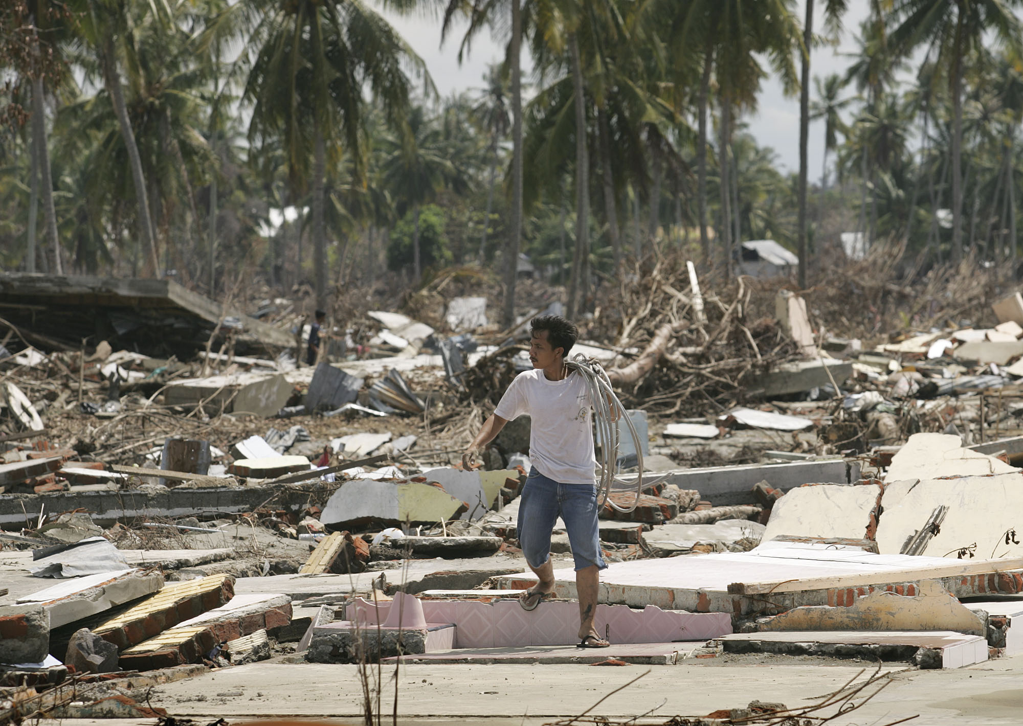 A man salvages electrical wire in January 2005 from an area of former beachfront homes that were flattened by the tsunami in Banda Aceh, Indonesia. This month marks the 10th anniversary of the Dec. 26, 2004, Indian Ocean tsunami. Photo by Mike DuBose, UMNS
