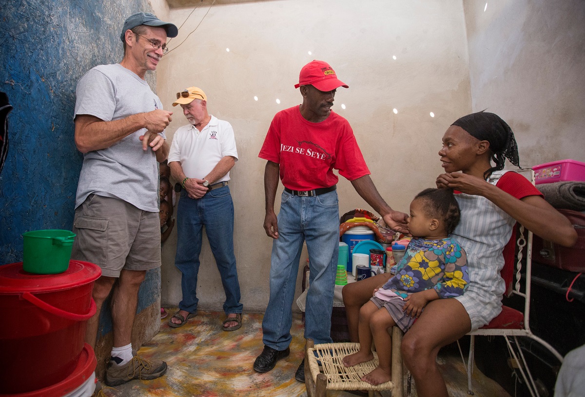 The Rev. Tom Vencuss (left) and Bill Borah visit with the Degazon family after they rebuilt their Port-au-Prince, Haiti, home with help from the Haiti Home Assistance Program in 2013. Vencuss lived in Haiti for three years as coordinator of the Haiti Response Plan.
