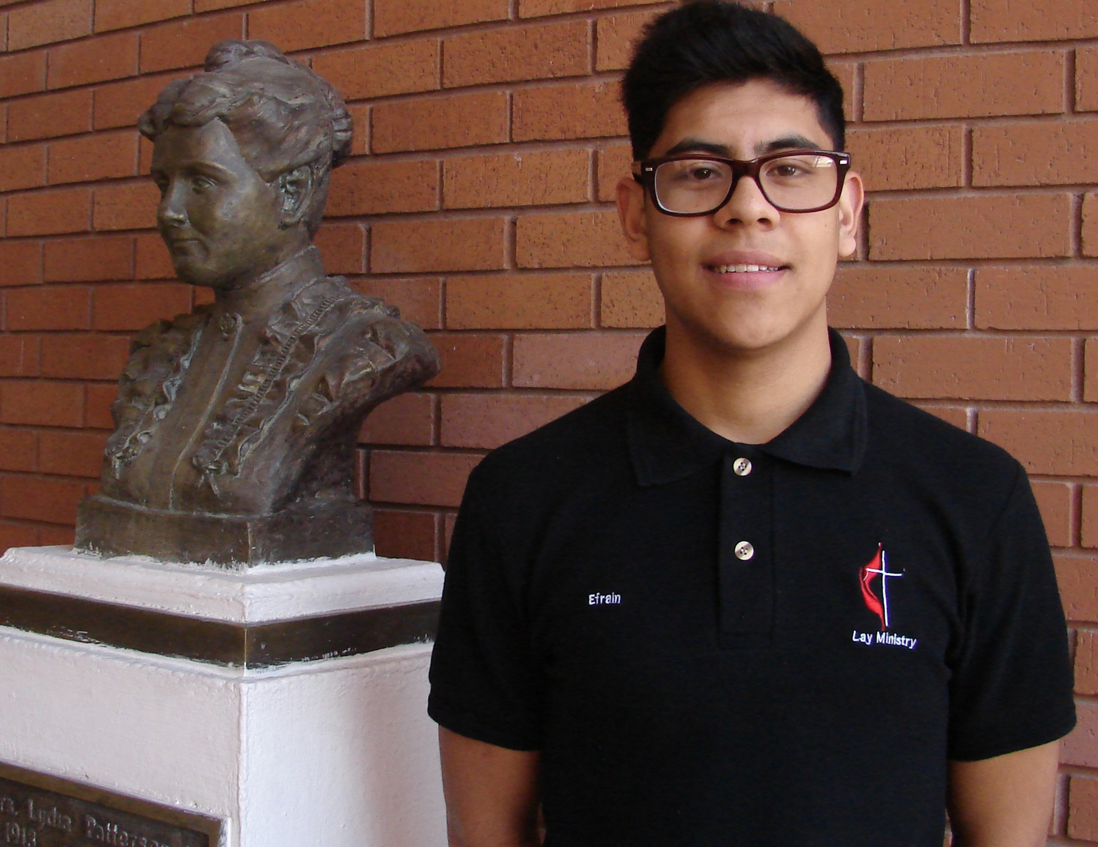 Efrain Belmontes is part of Lydia Patterson Institute’s lay ministry program, which places students in United Methodist churches in the summer to help with Hispanic ministries. He’s standing next to a bust of Lydia Patterson. Photo by Sam Hodges, UMNS