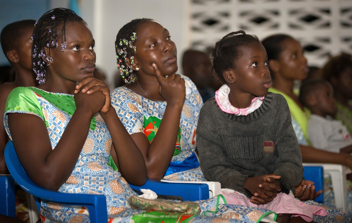Young people listen to a presentation about preventing the spread of Ebola prepared by United Methodist Communications during a service at the United Methodist Church in Sassandra. From left are: Anaya Grace Camara, 22; Flore Diobo, 30; and Marie Yao, 9.